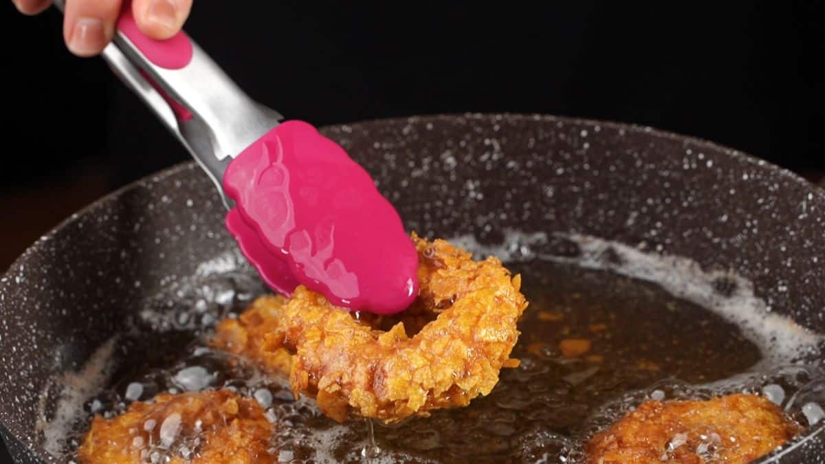 pink tons removing chicken ring from skillet