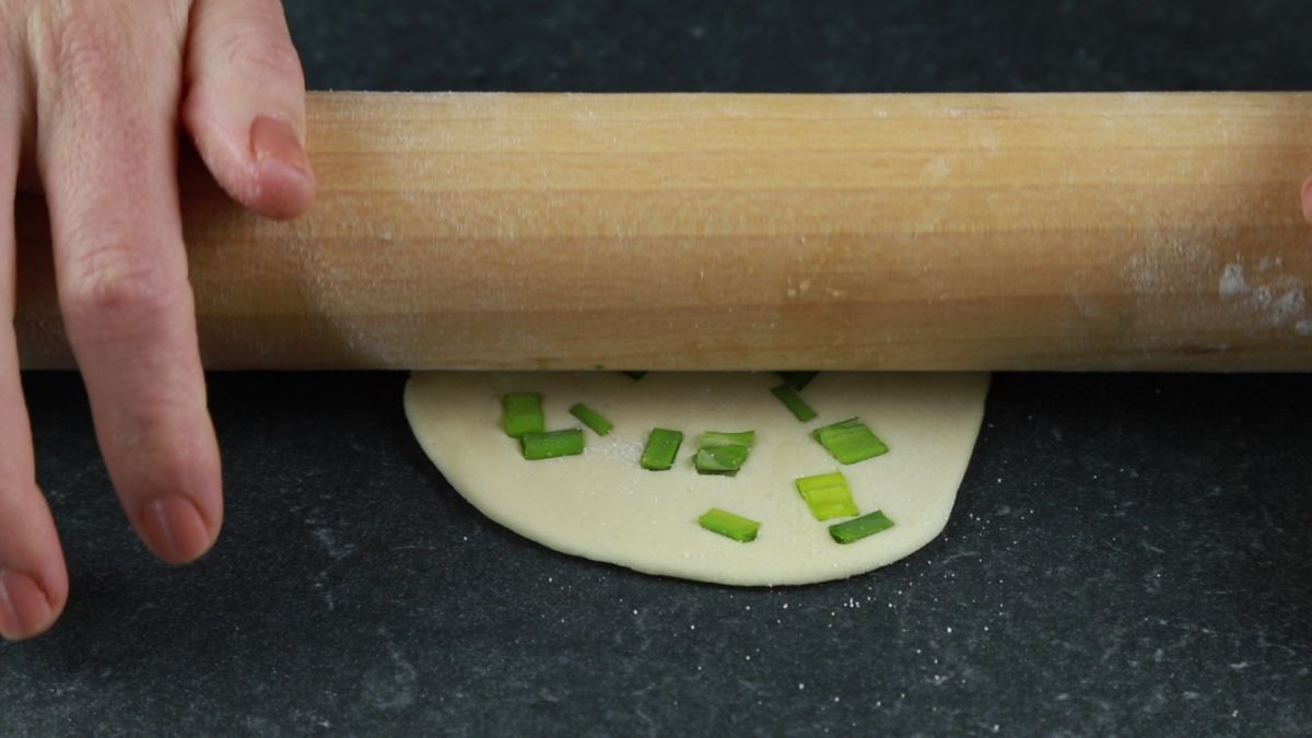 rolling pin on top of round dumpling wrapper