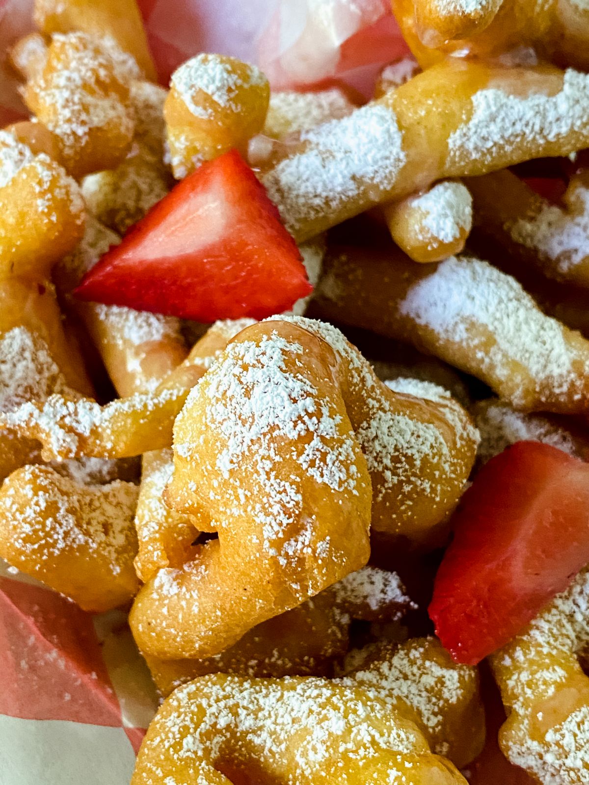 funnel cake fries with powdered sugar and sliced berries on top