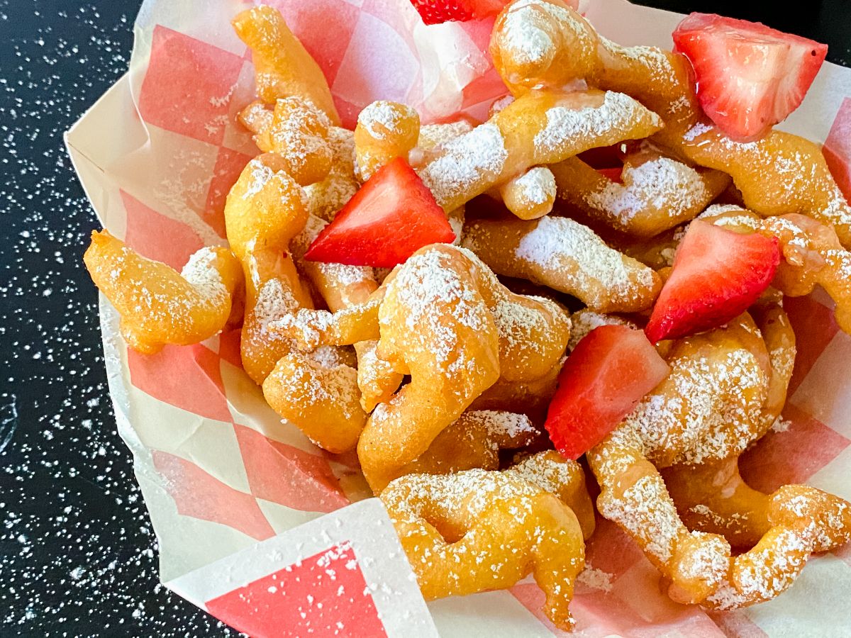 red and white basket of funnel cake fries on black table