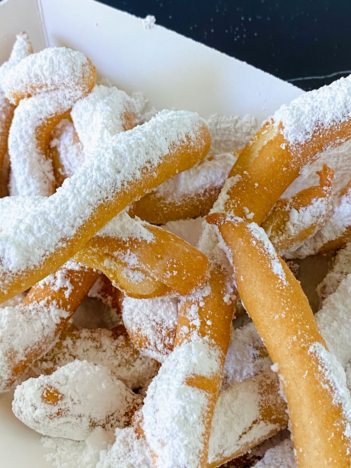 funnel cake fries dusted with powdered sugar in white basket