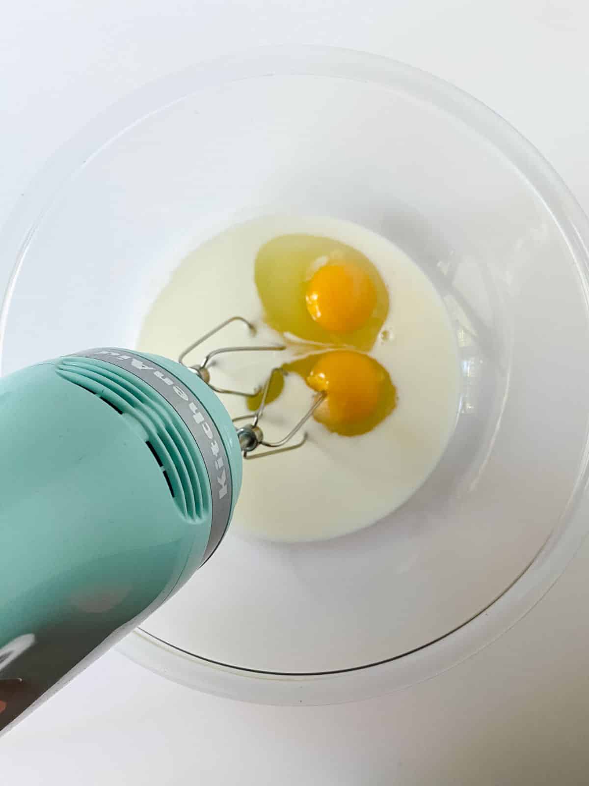 eggs and milk in bowl with hand mixer