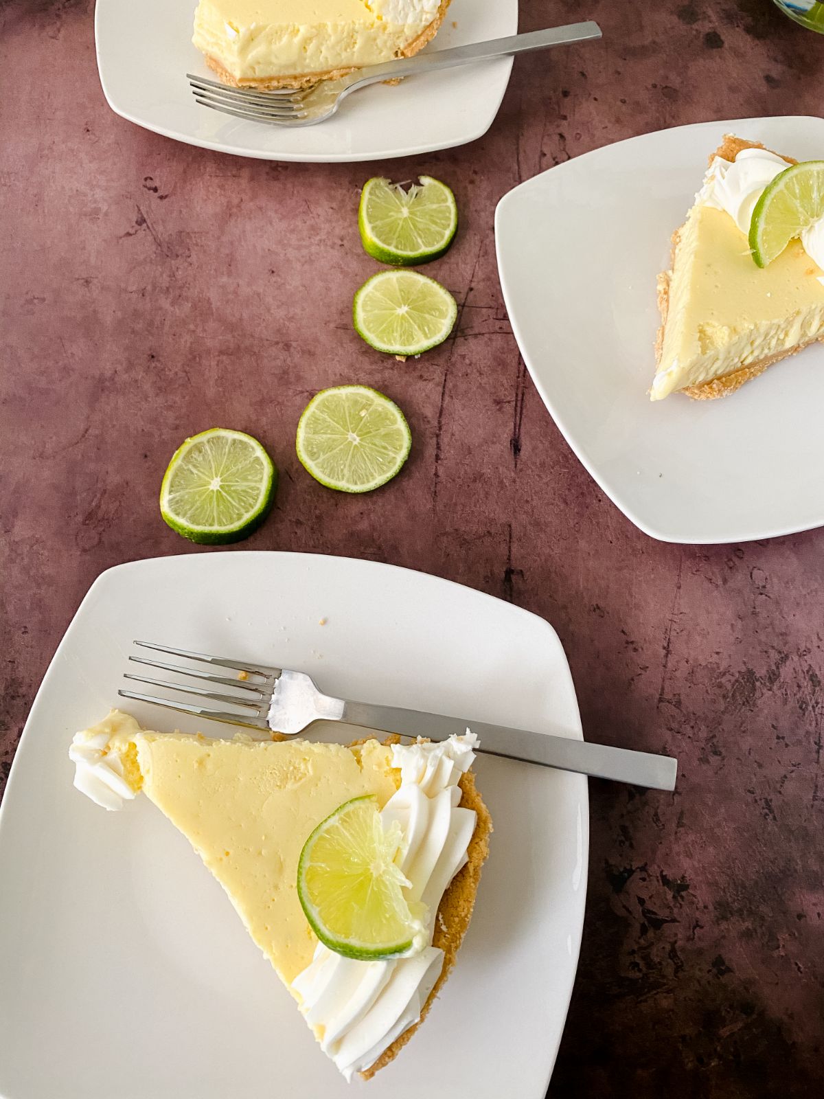 slice of key lime pie on white plate with sliced limes on table