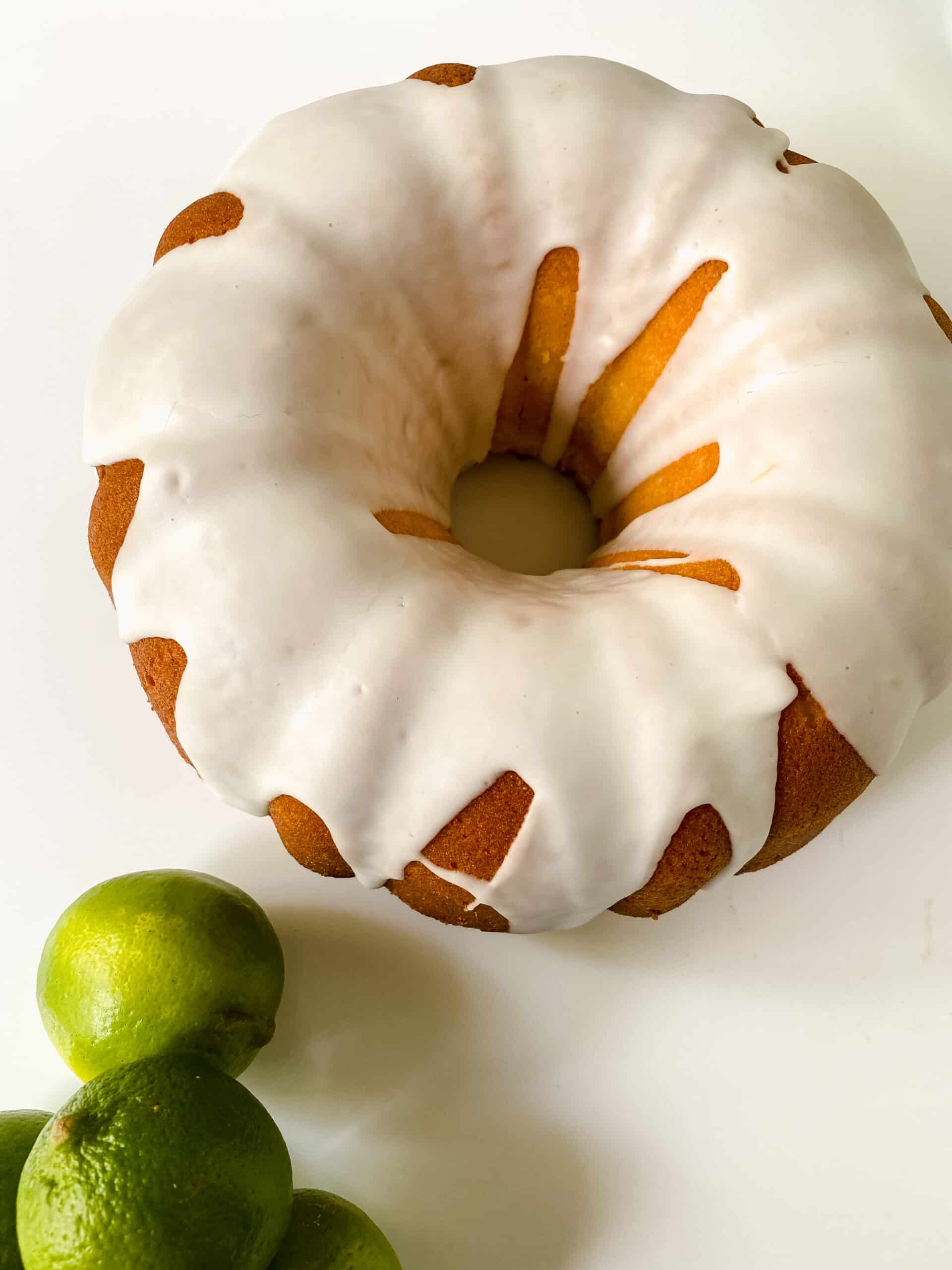 bundt key lime pound cake on white table by whole limes