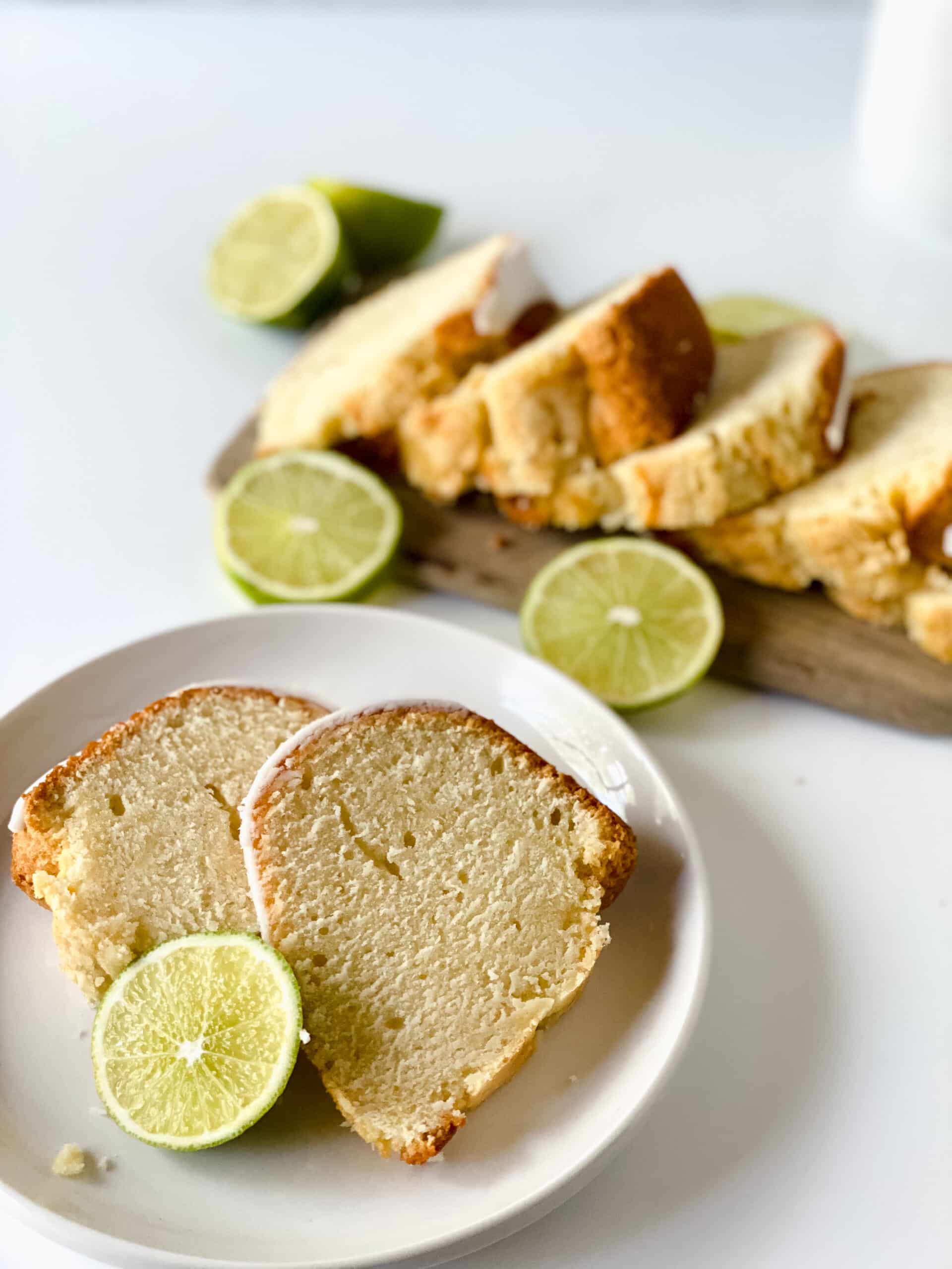 white plate with two slices key lime pound cake next to sliced cake