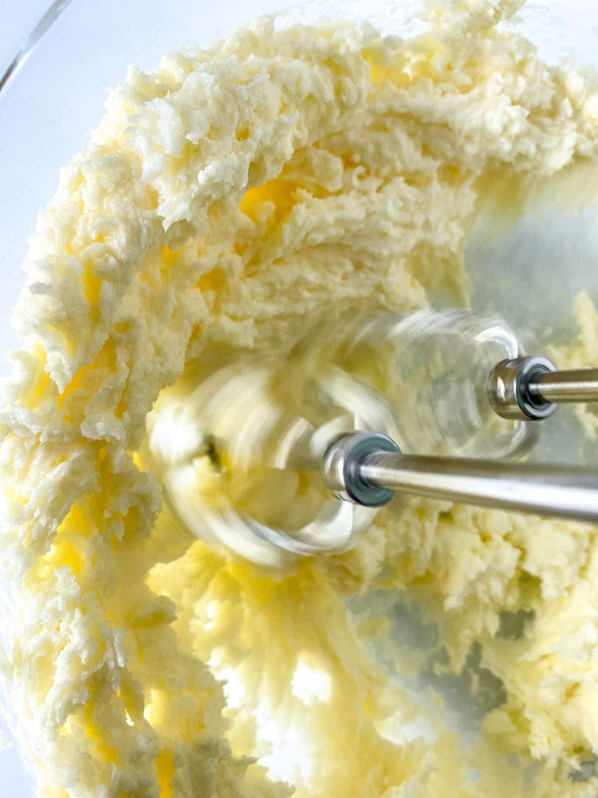 hand mixer beaters in glass bowl of butter