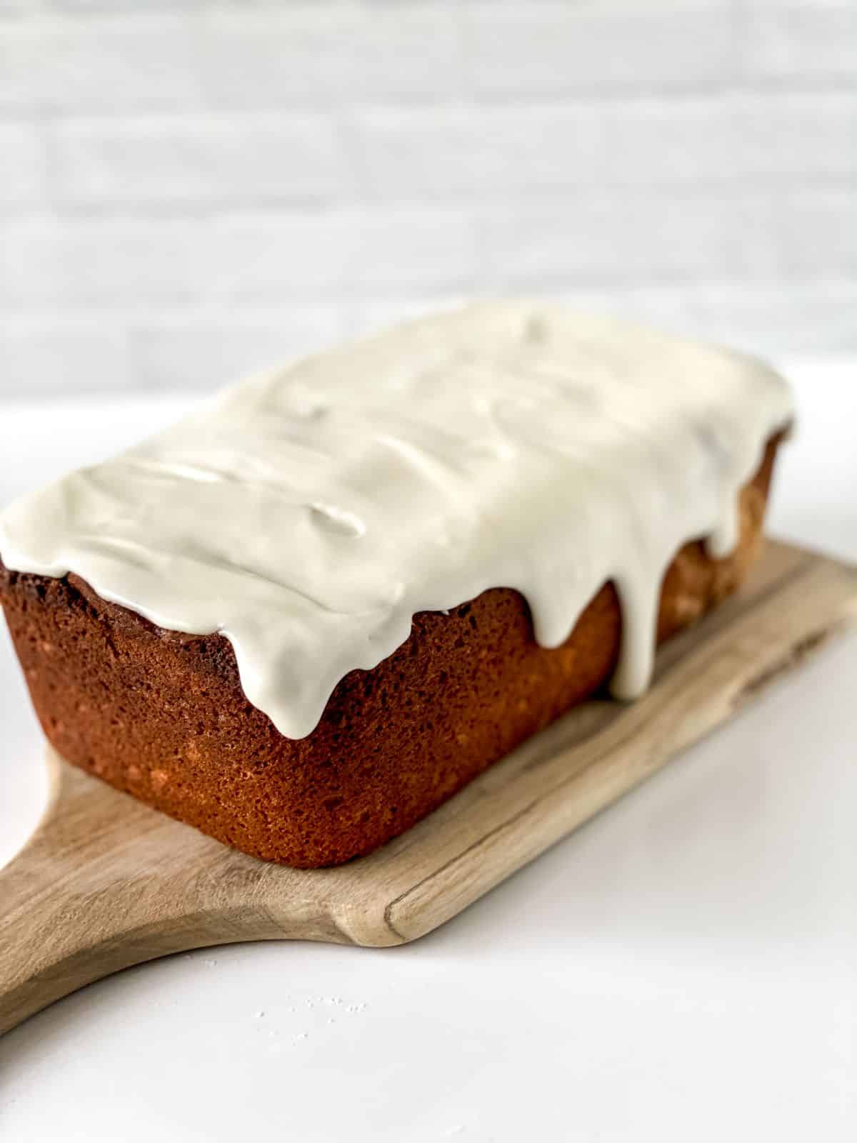 cutting board with lemon loaf on top sitting on white table