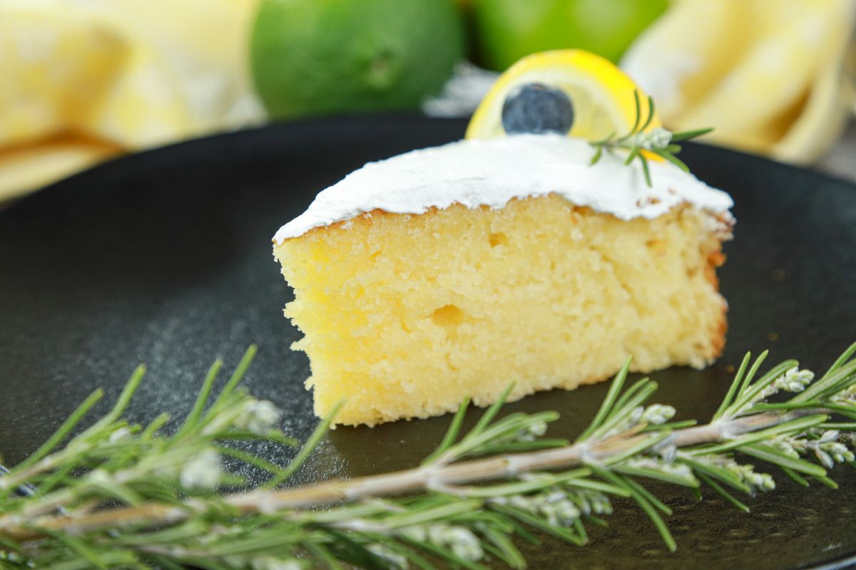 rosemary sprig on black plate by lemon cake slice