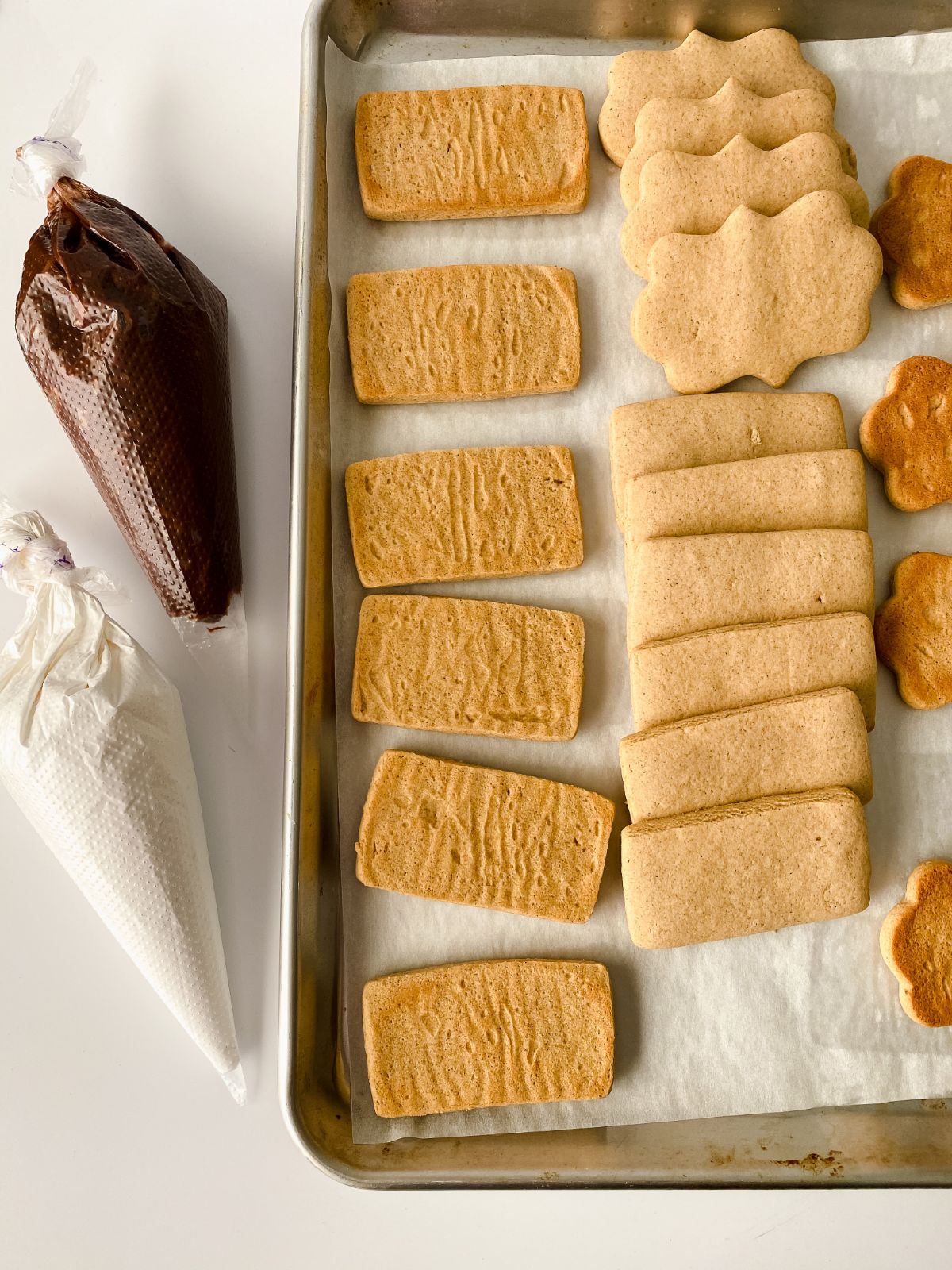 graham crackers on baking sheet by chocolate and marshmallow in piping bags