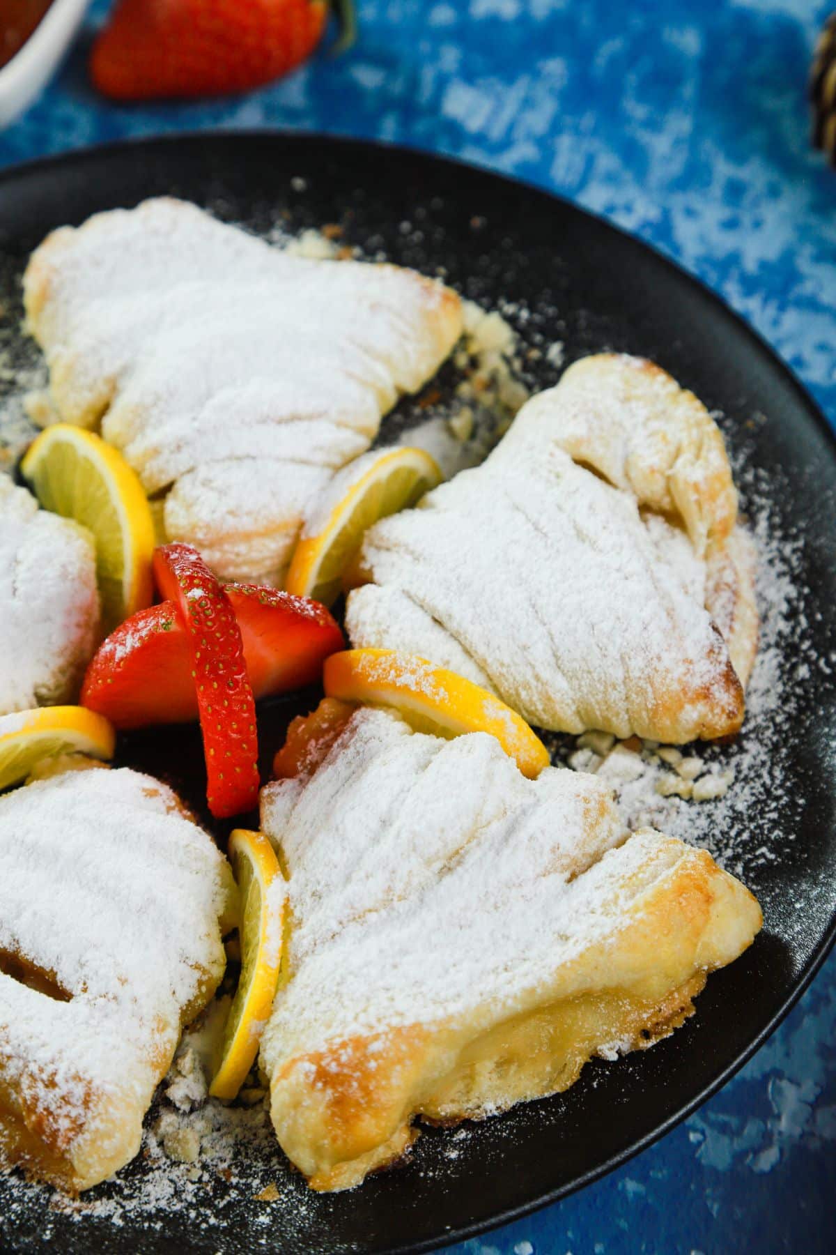 powdered sugar dusted sfogliatelle on black plate with fresh berries