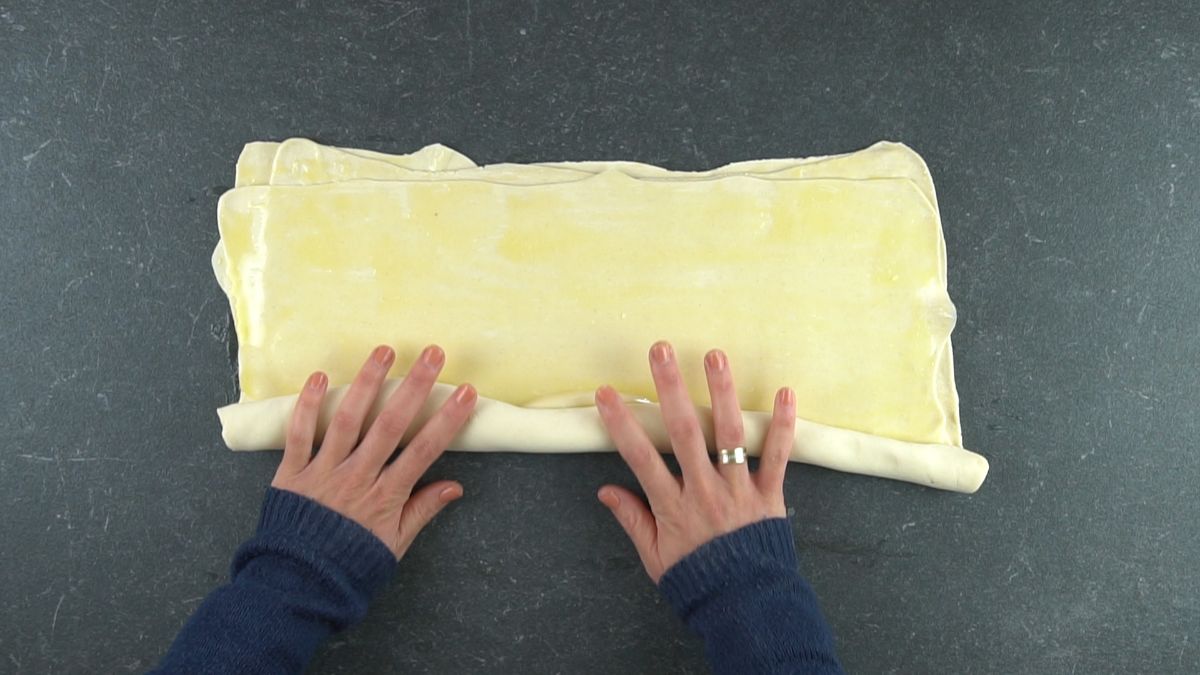 pastry dough being rolled into tube before cutting