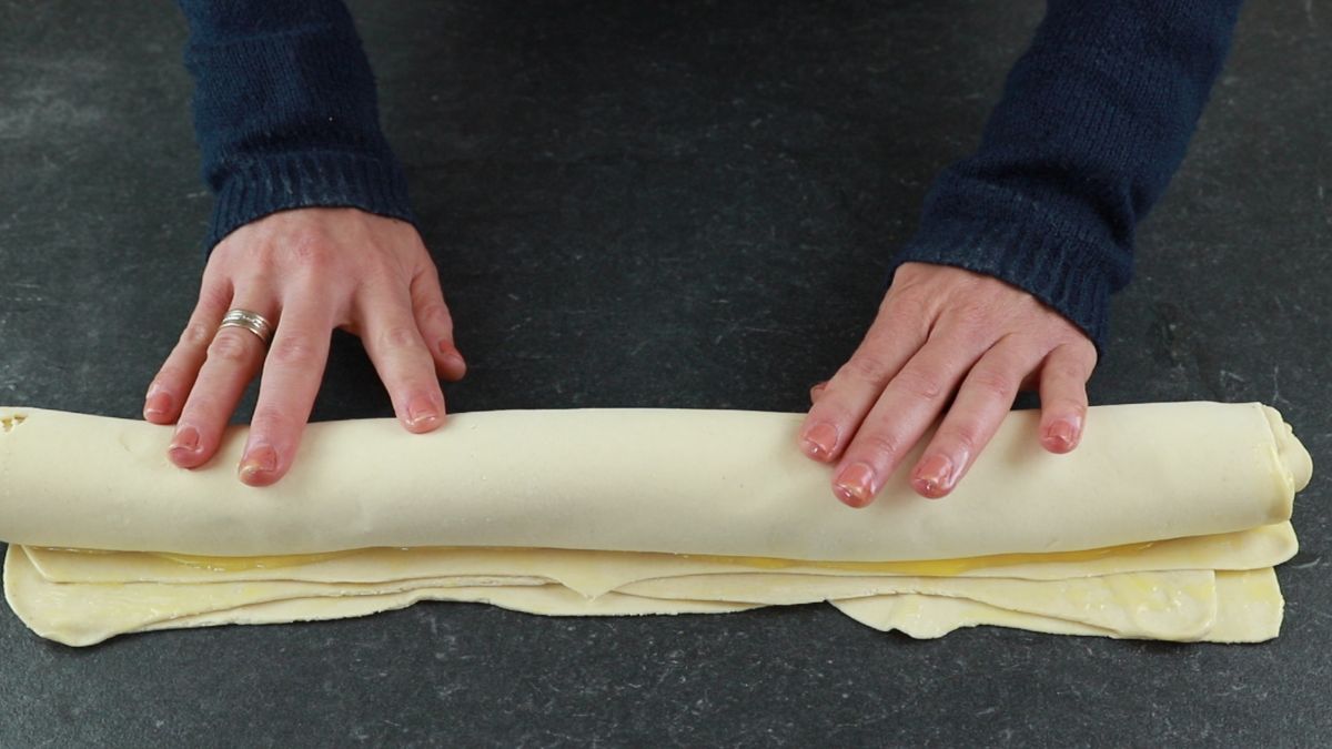 hands rolling pastry dough into log