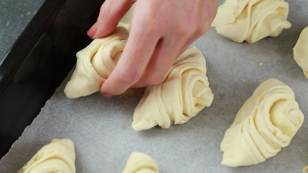 hand placing raw sofliatelle on baking sheet