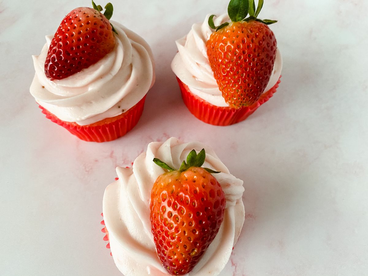 three homemade strawberry cupcakes on white table