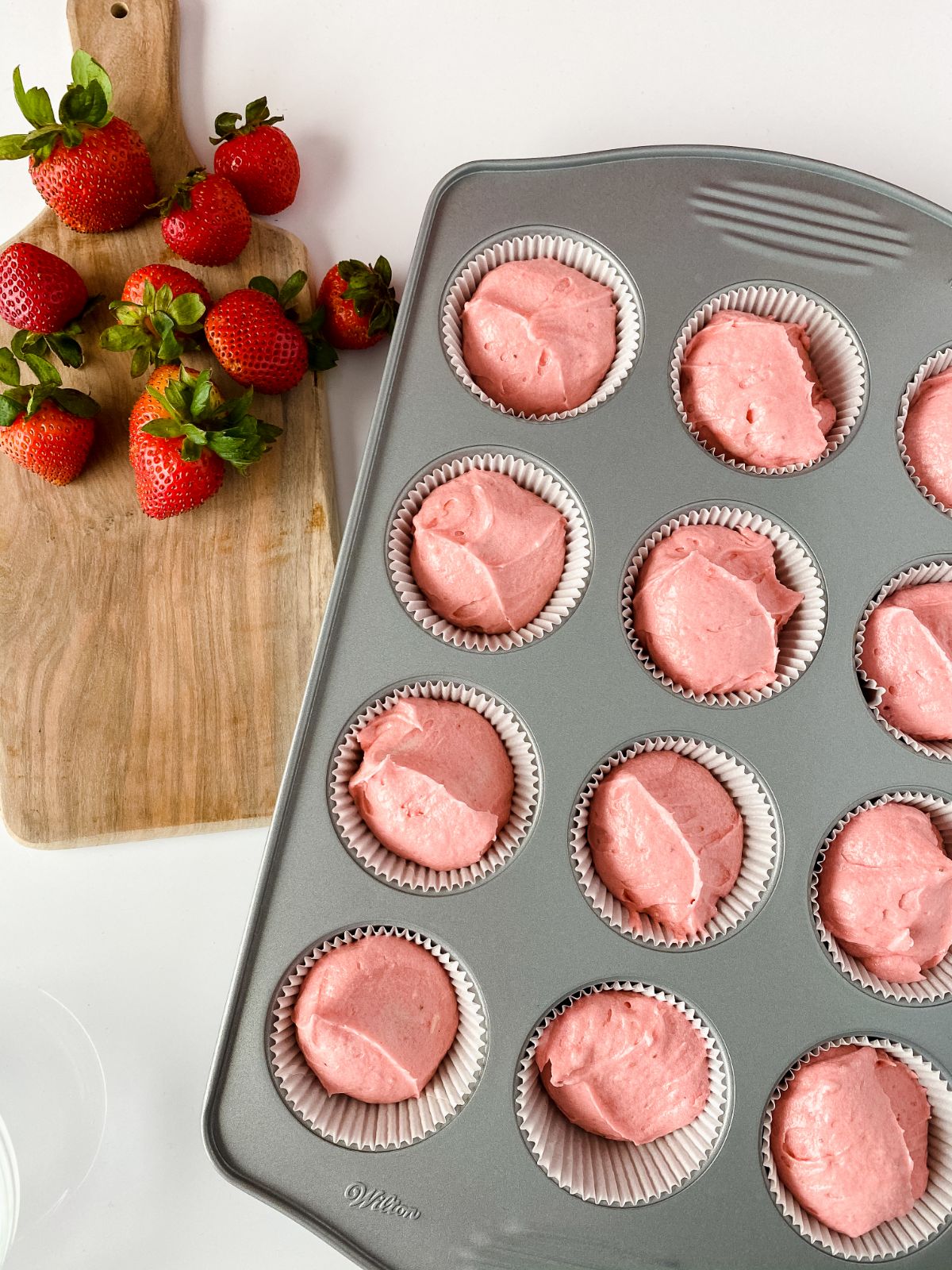cake batter in baking tin by cutting board of berries