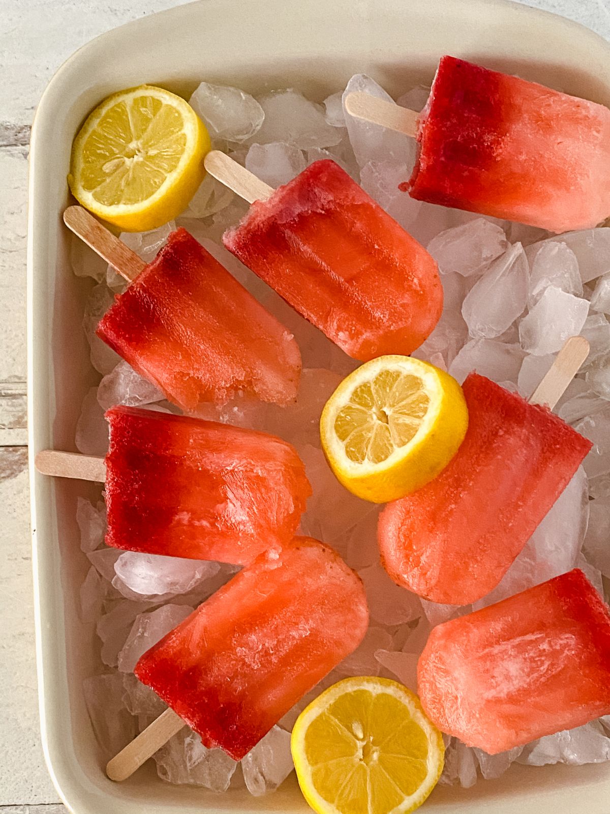 pink ice pops on ice by lemon slices