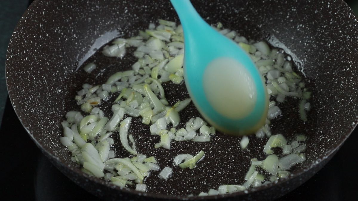 blue spoon in skillet with onions