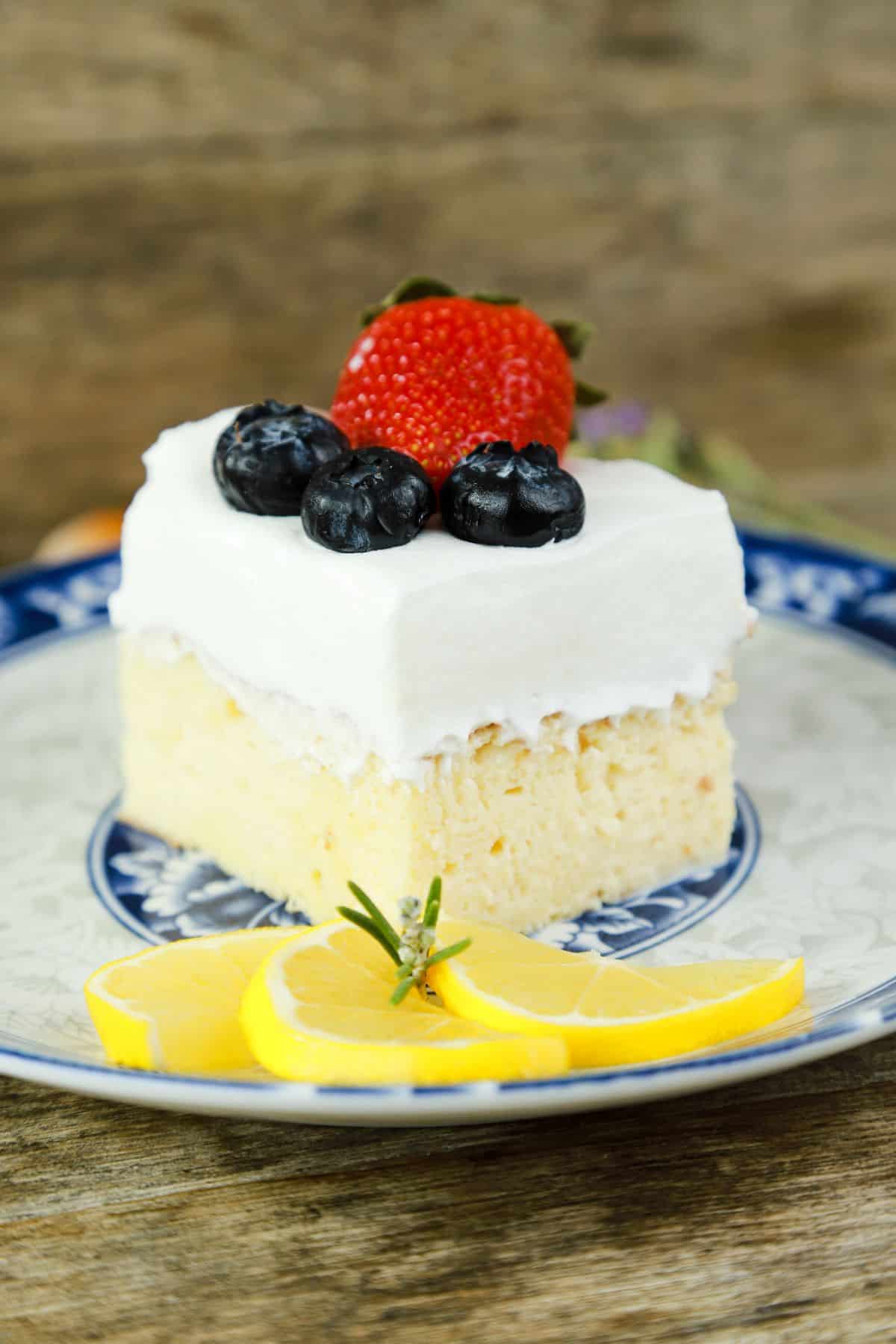 single slice of tres leches cake topped by strawberry and blueberries