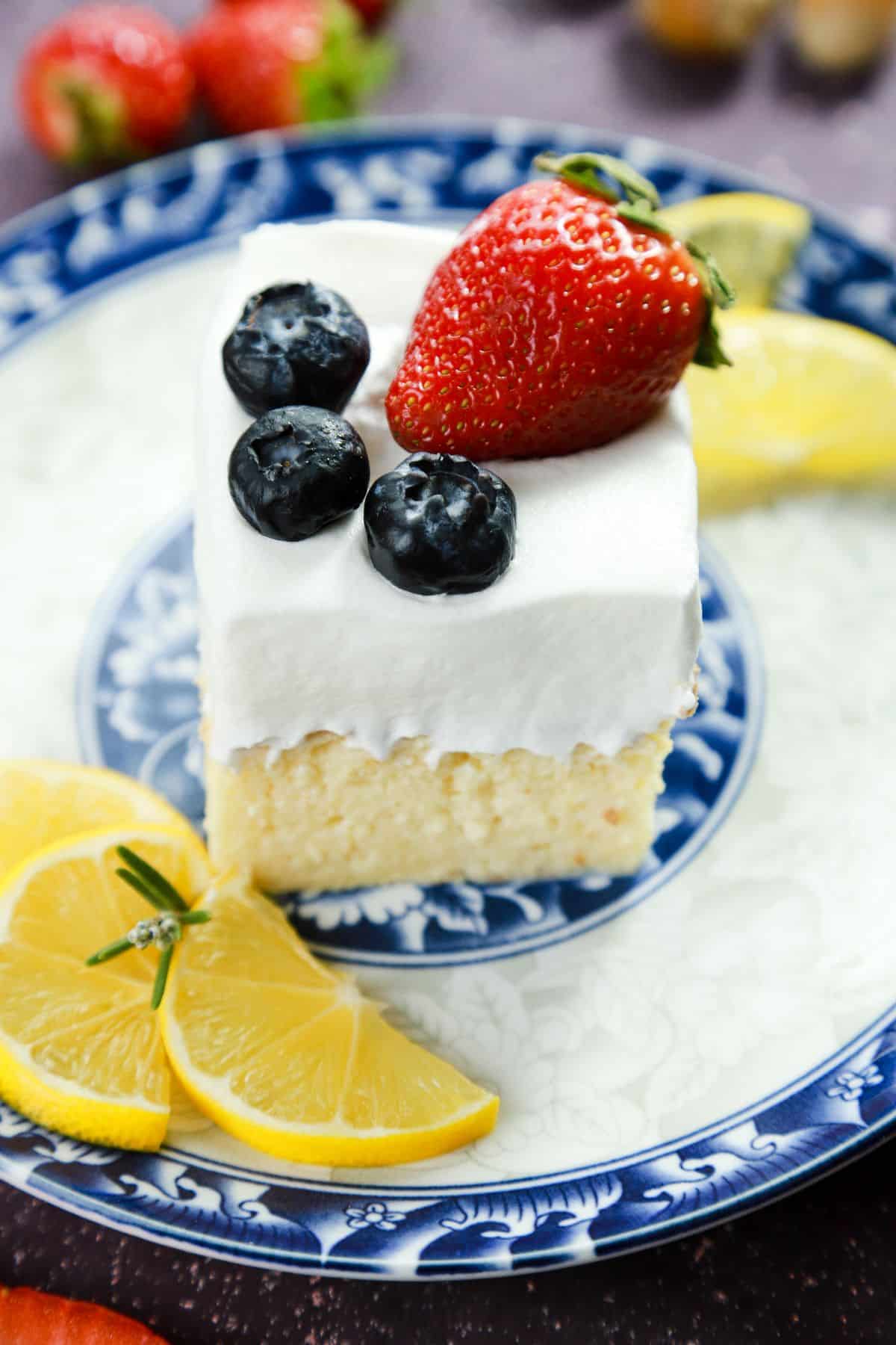 slice of cake topped with berries on white and blue plate