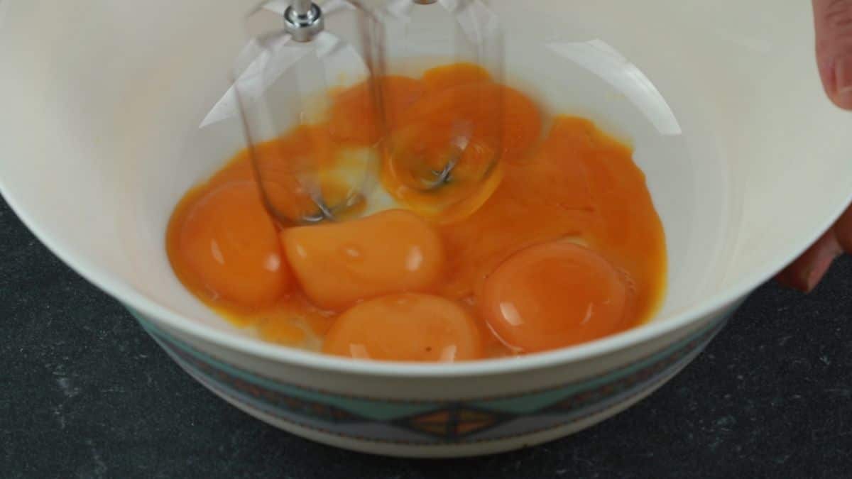 hand mixer beating eggs in white bowl