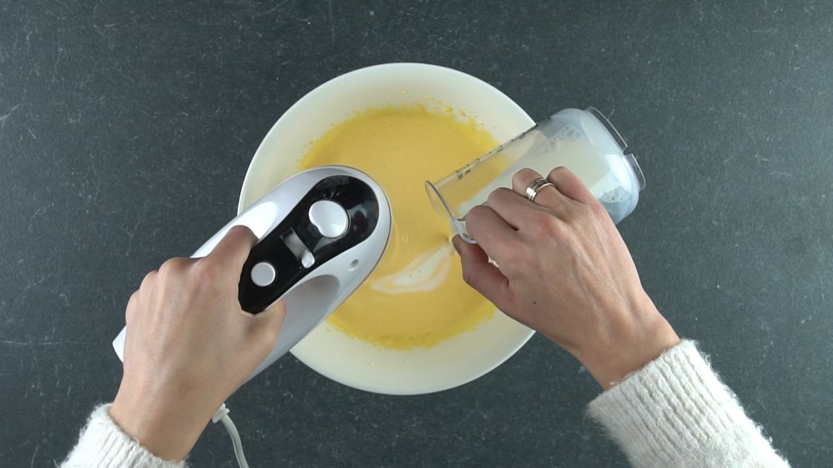 hand mixer in white bowl beating eggs and milk