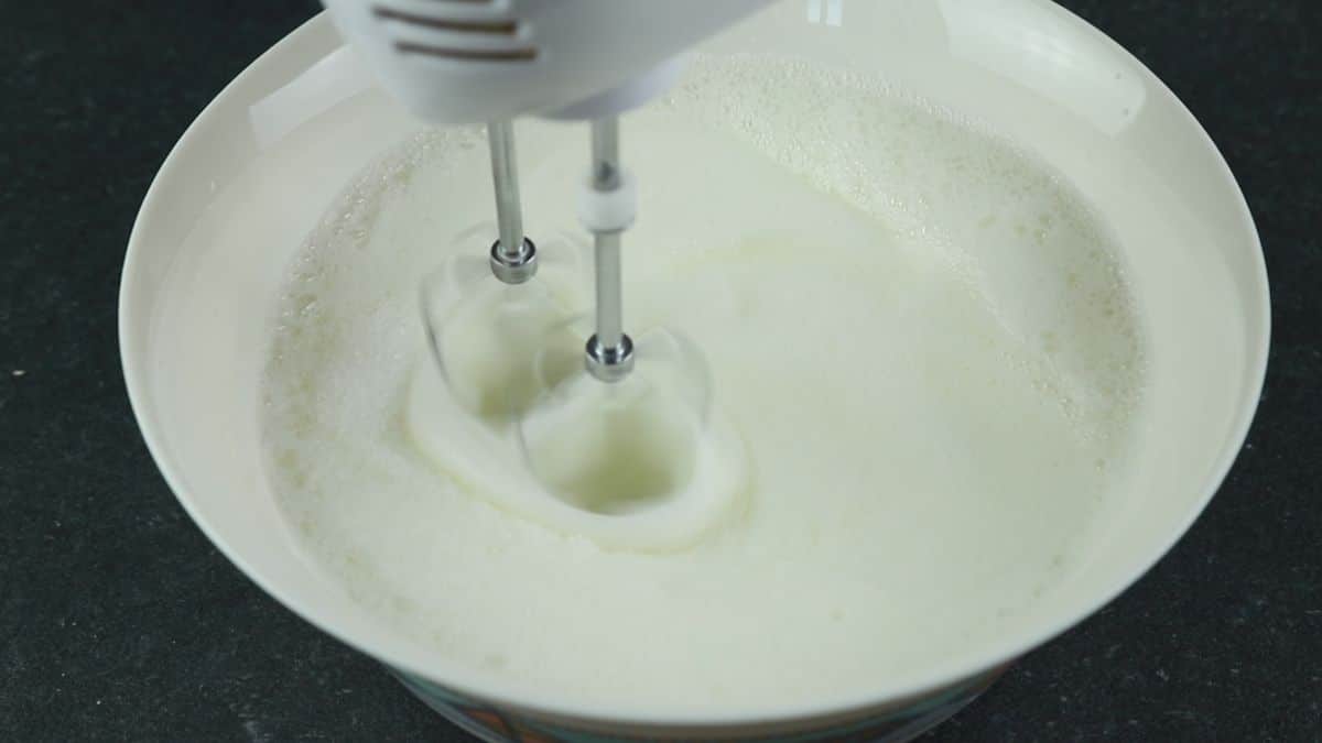 hand mixer in white bowl of egg whites
