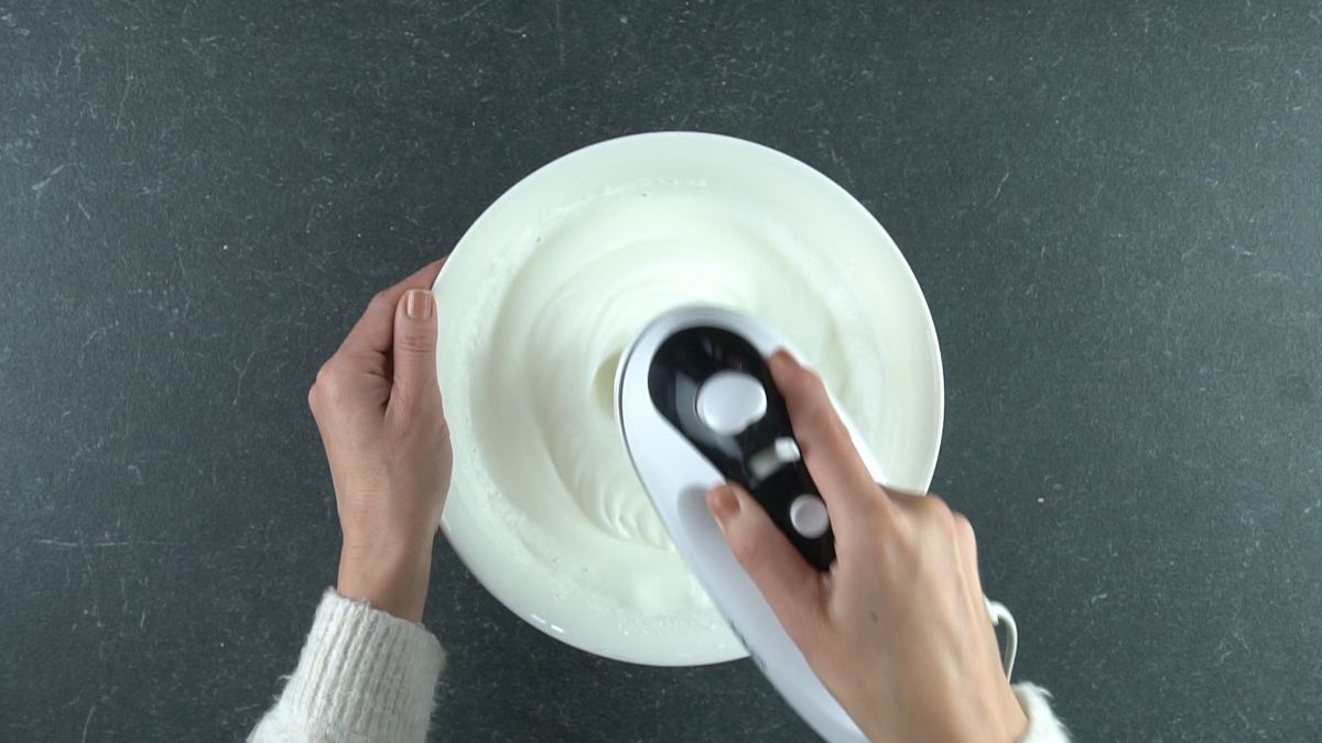 egg whites being beaten in large white bowl