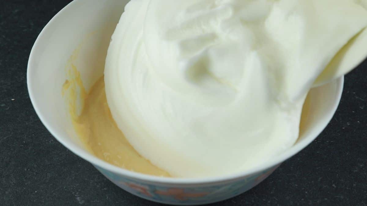 egg whites being poured into cake batter