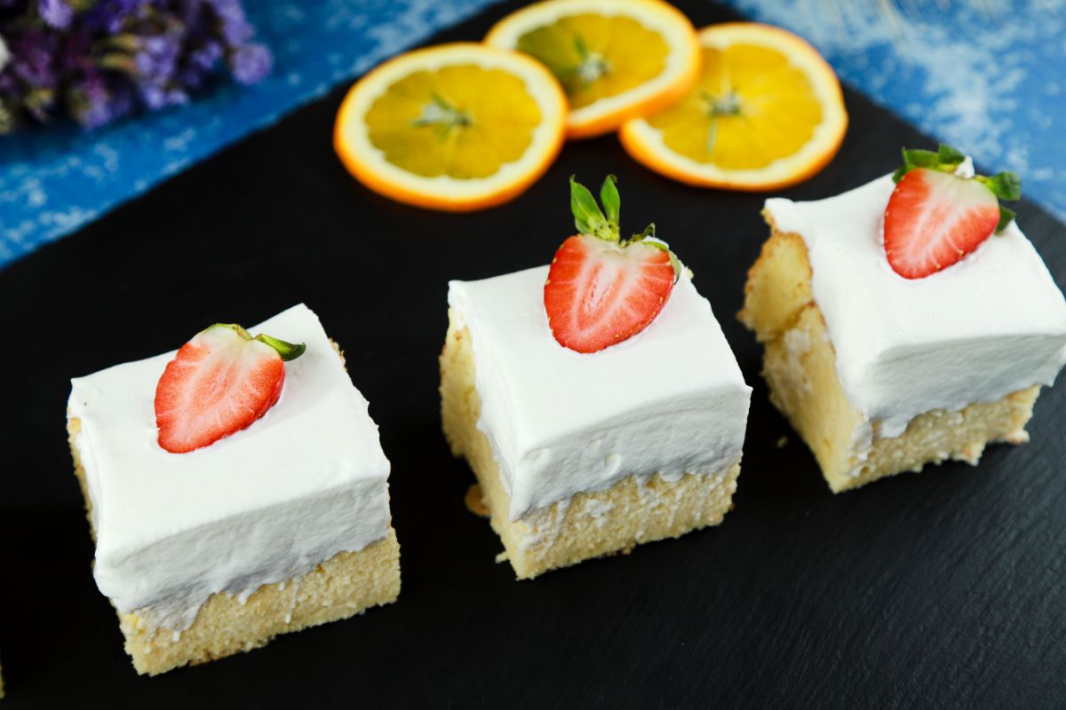 three slices tres leches cake on black plate with orange slices