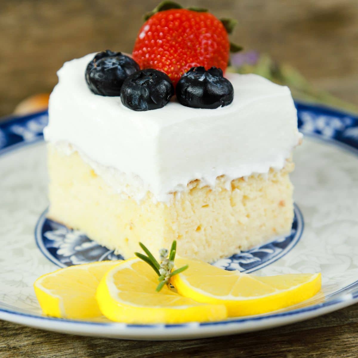 slice of cake topped with berries on white and blue plate