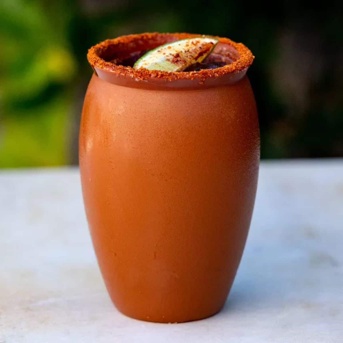 Cantarito cocktal with a slice of lime in a clay pot.