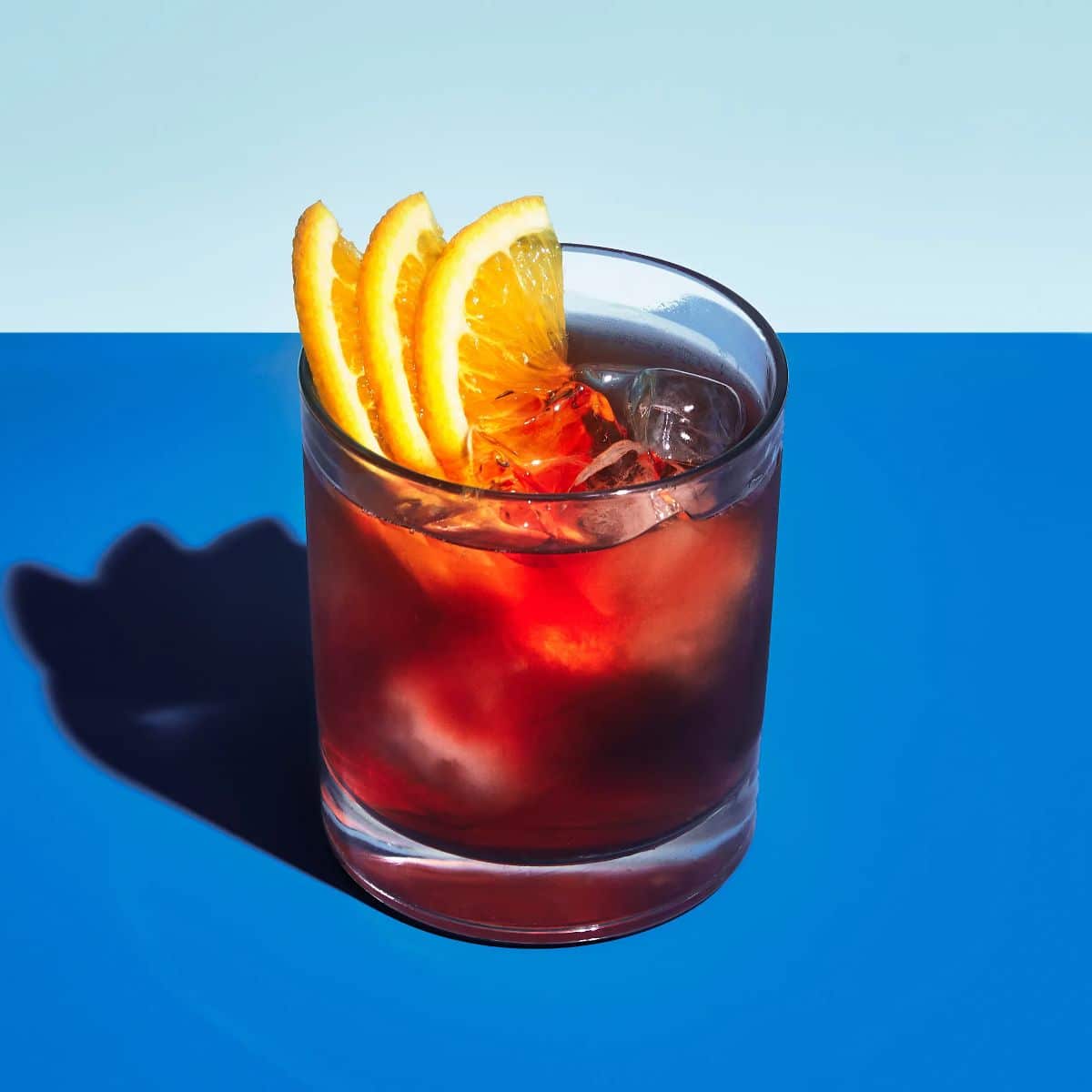Negroni cocktail with slices of orange, ice cubes in a glass cup.