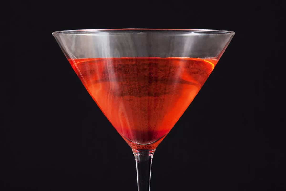 English Rose Martini in a tall glass cup on a black background.