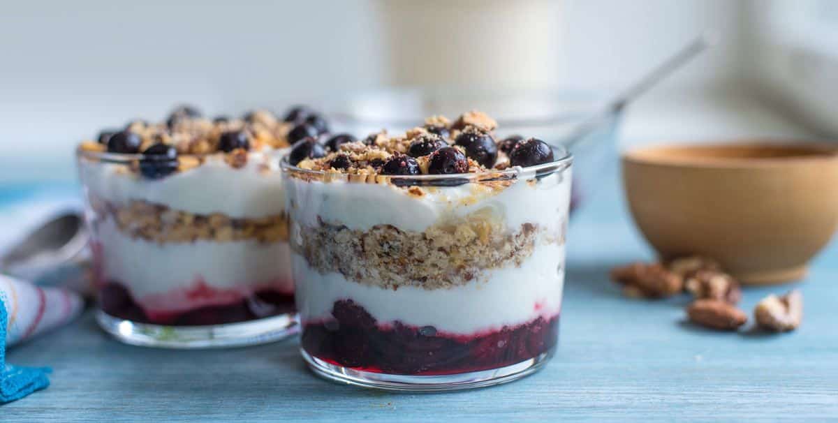 Greek Yogurt Parfait with fruits and nuts on the top in glass cups.