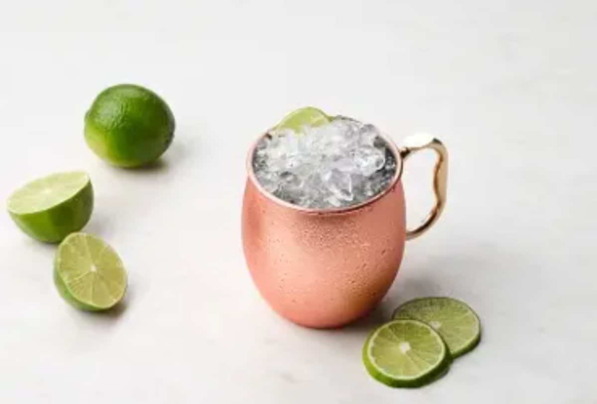 British Mule gin cocktail in a metal cup with slices of lime scattered around.