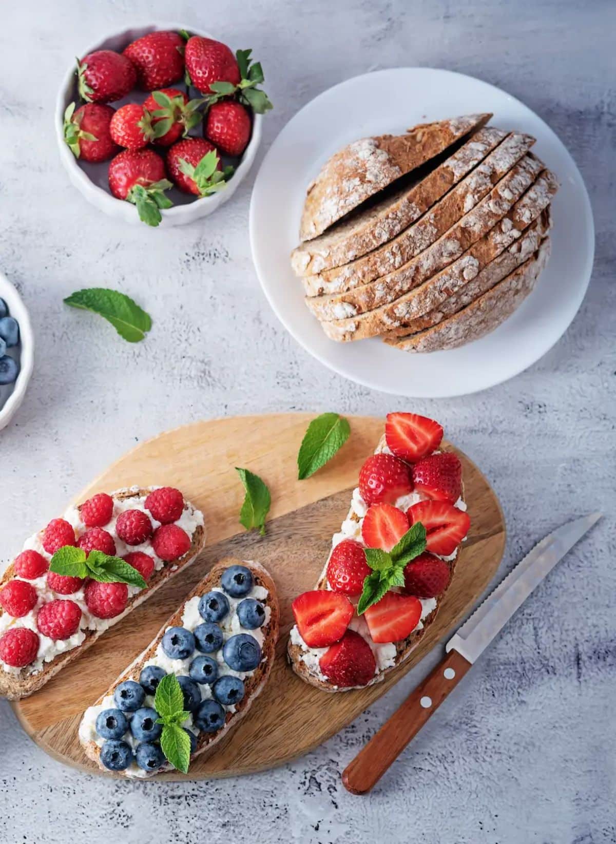 Cottage Cheese Toasts With Fruits on a wooden cutting board.