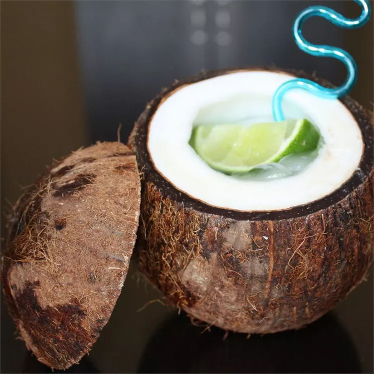 Coco Loco cocktail in a coconut shell with a straw and a piece of lime.