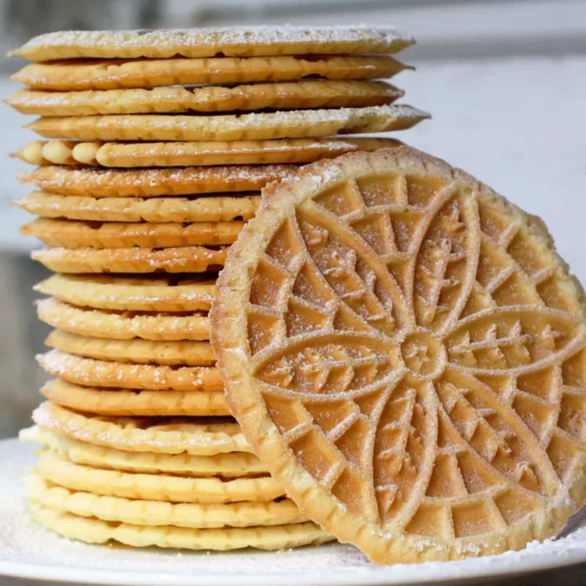 A stack of Pizzelle Cookies on a white plate.