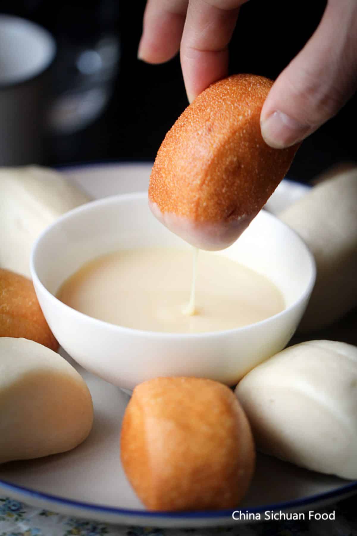 Fried Mantou with Condensed Milk held by a hand.