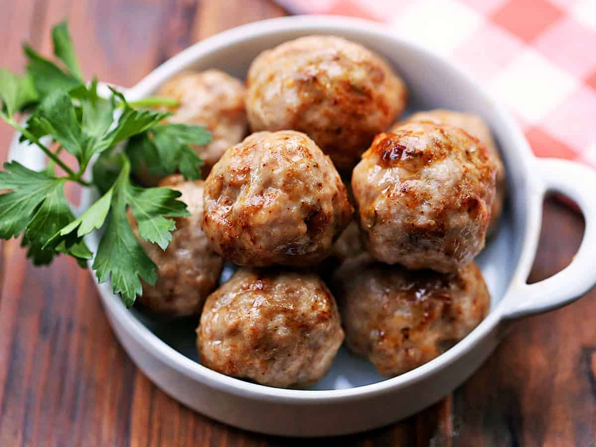 Ground Pork Meatballs in a white bowl with a herb,