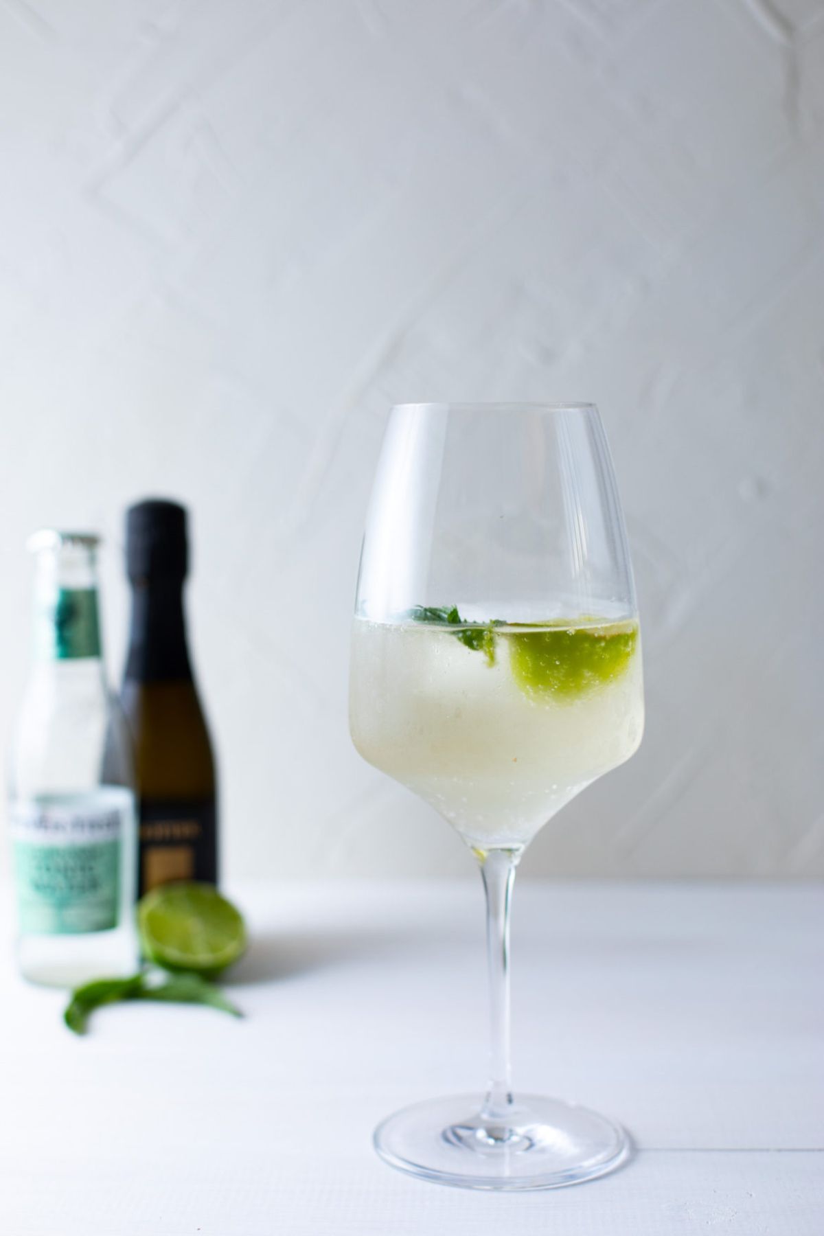Elderflower Gin Spritz cocktail in a tall glass with a lime and mint.