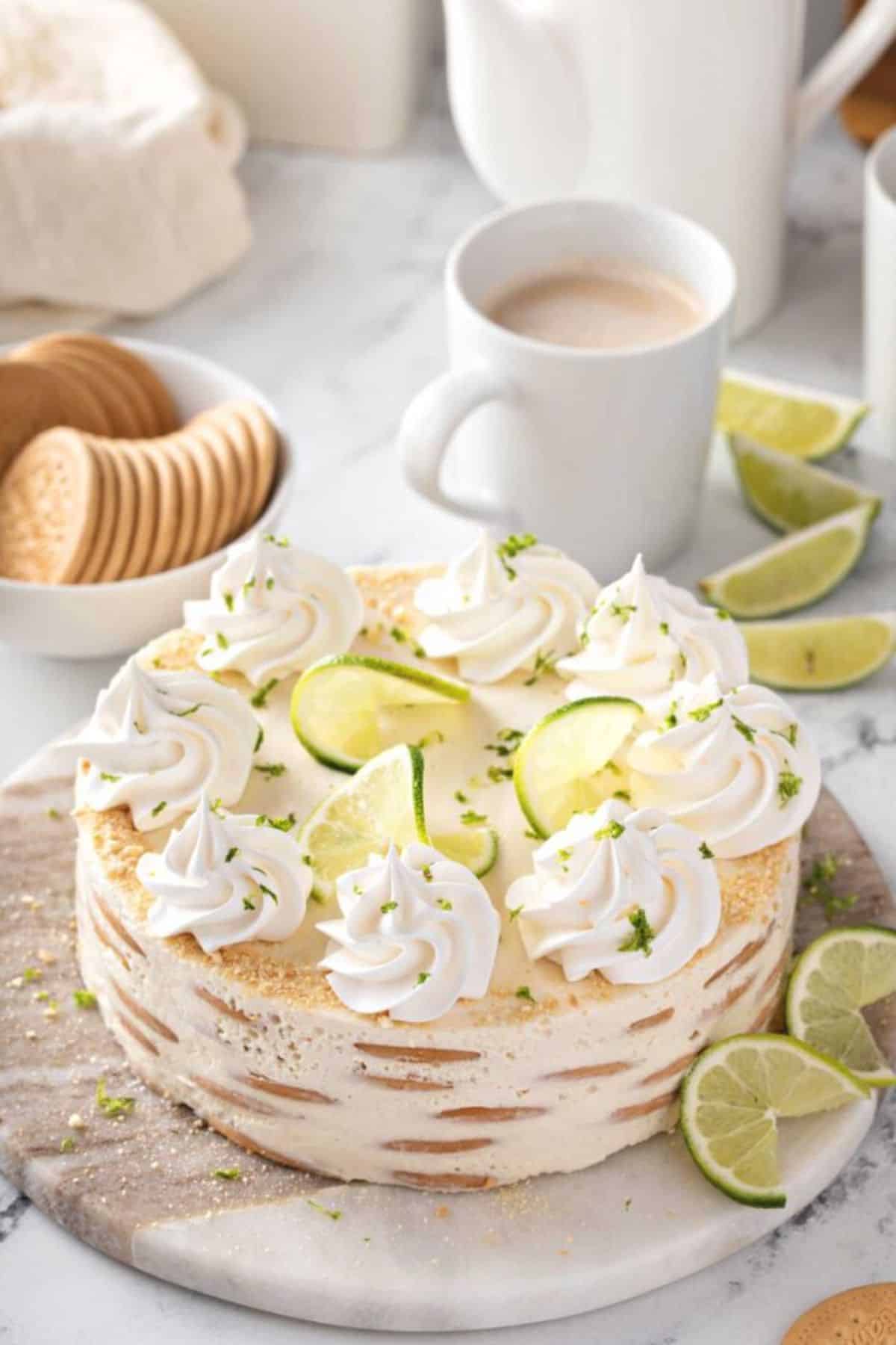 Carlota de Limón mexican cake with slices lime on the top on a wooden board.