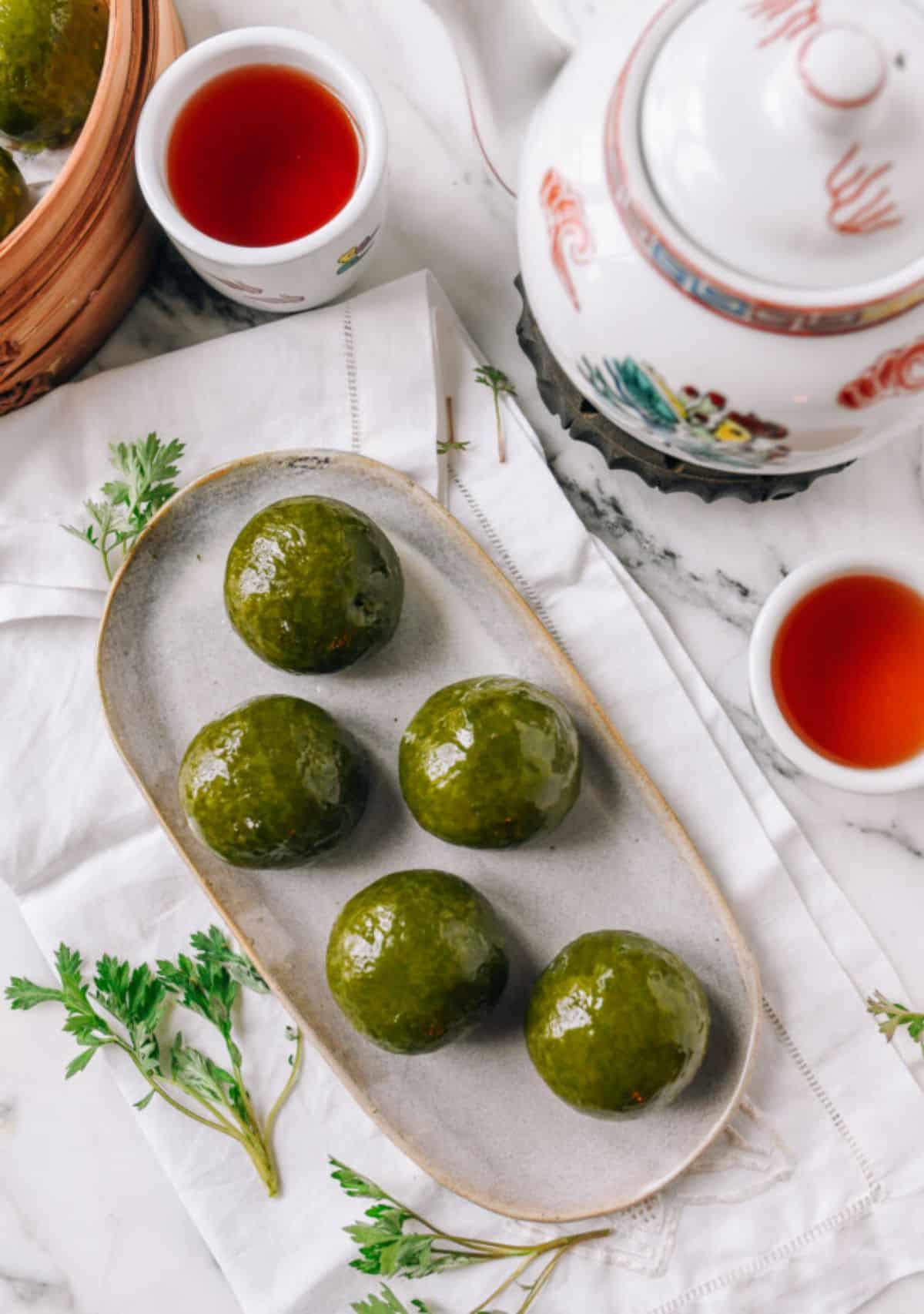 Qingtuan (Sweet Green Rice Balls) on a gray tray.