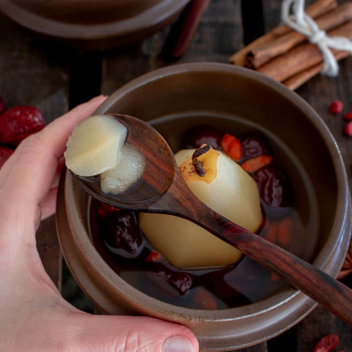 Chinese Pear Dessert Soup in a brown bowl picked by a wooden spoon.