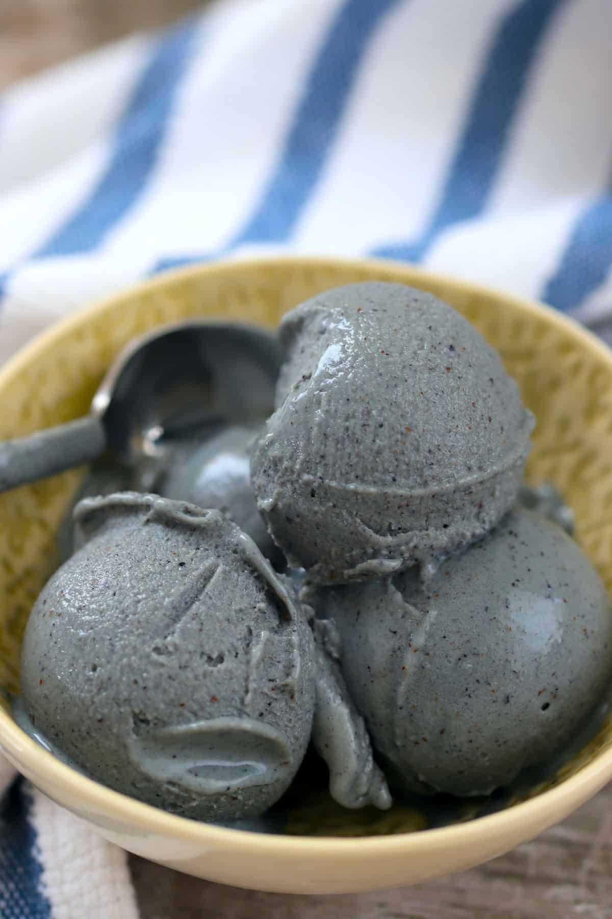 Protein Blueberry Ice Cream in a brown bowl with a spoon.