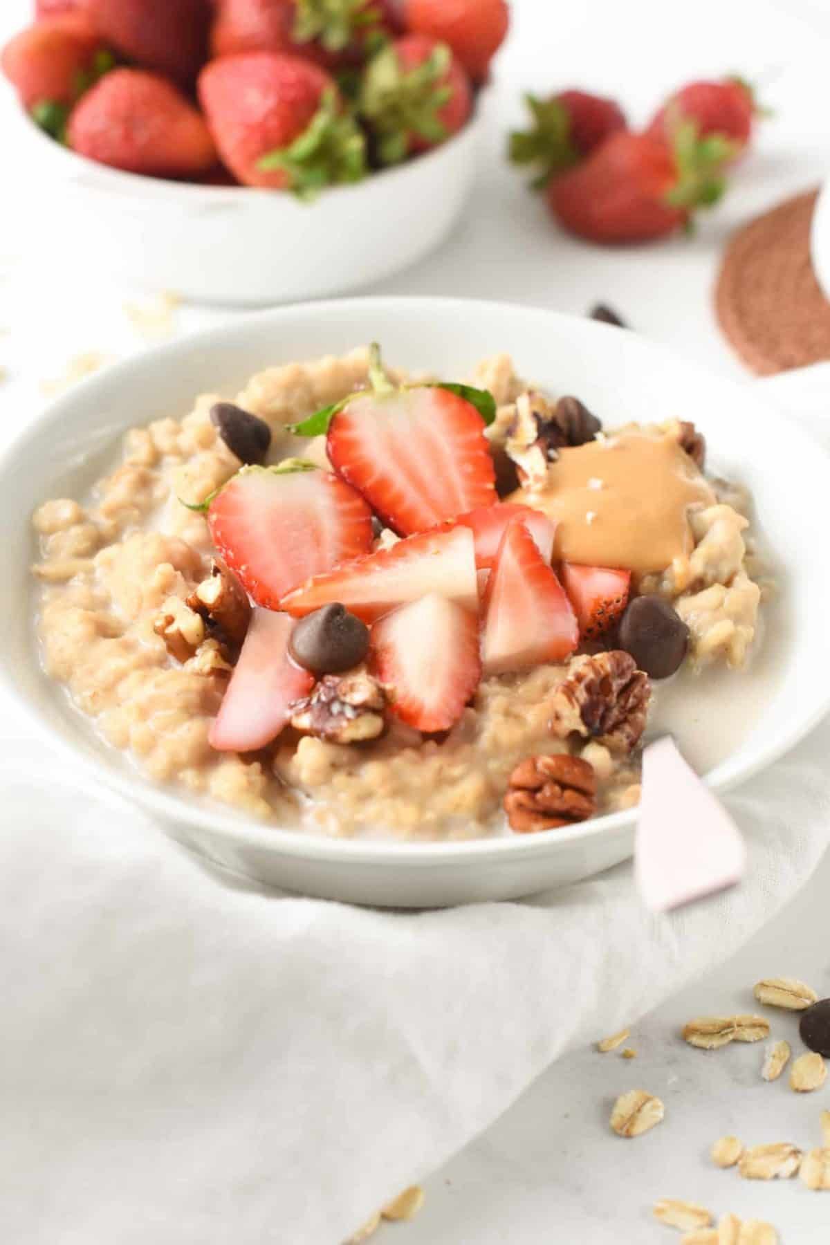 Protein Powder Oatmeal with fruits, nuts in a white bowl.