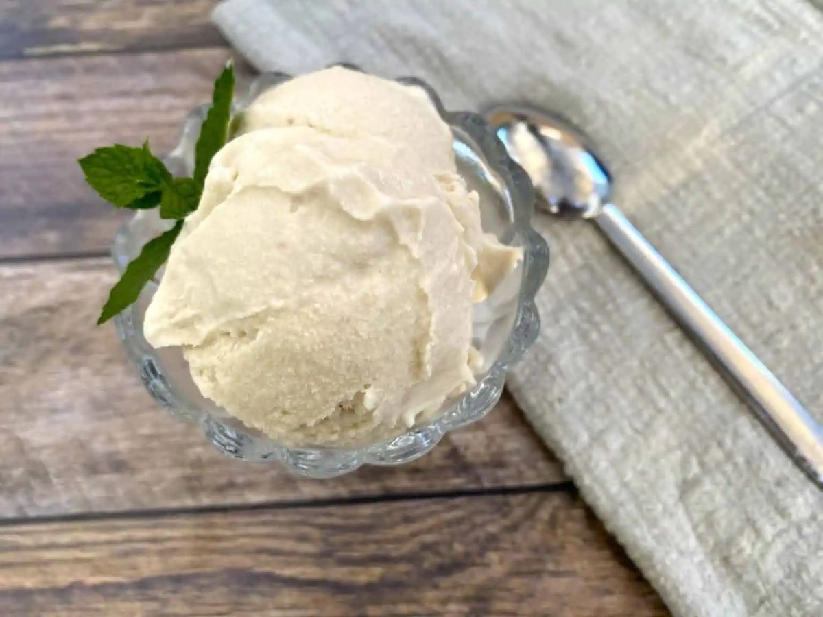 Ninja Creami Keto Vanilla Ice Cream in a glass cup on a wooden table with a spoon.