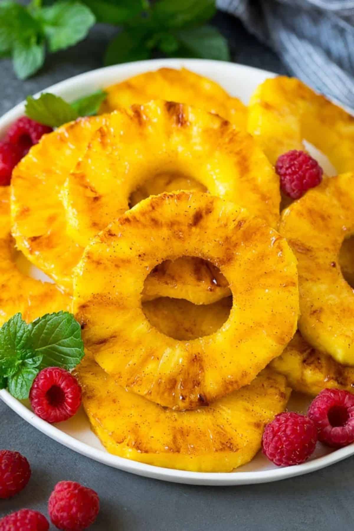 Grilled Pineapples with raspberries on a white plate.