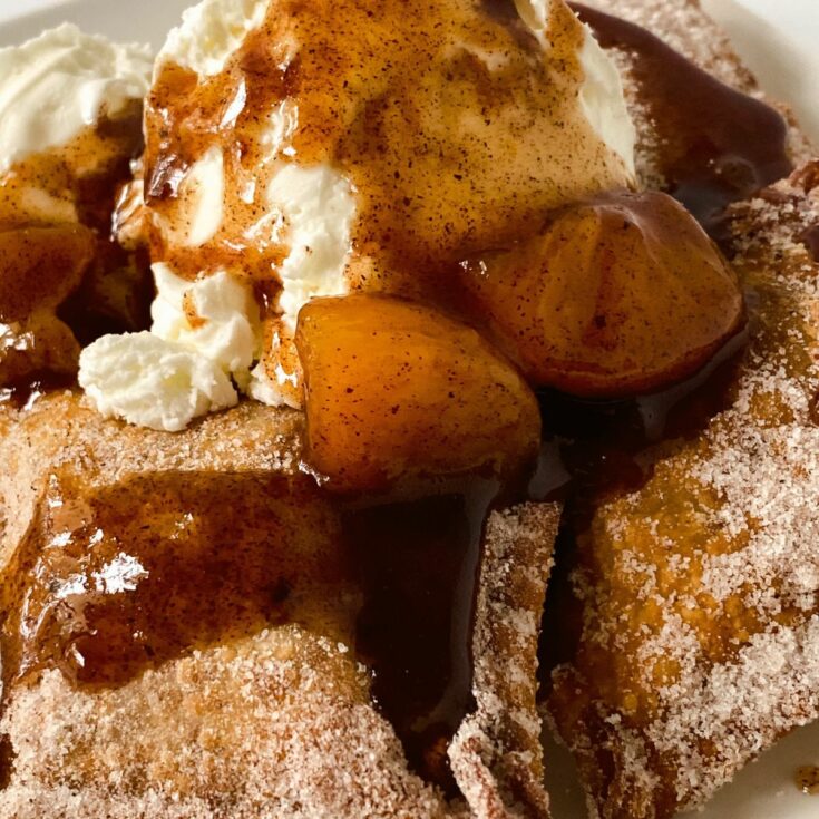 peach cobbler dessert wontons topped by ice cream and sauce