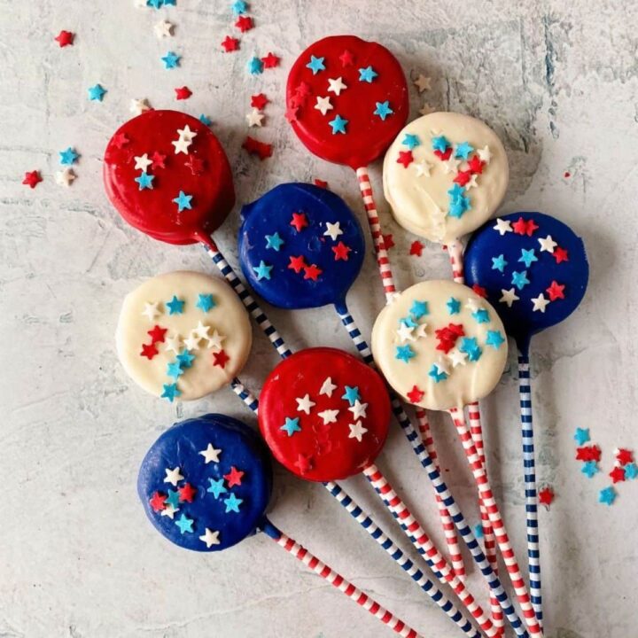 red white and blue dipped oreo cookies with striped handles on white table
